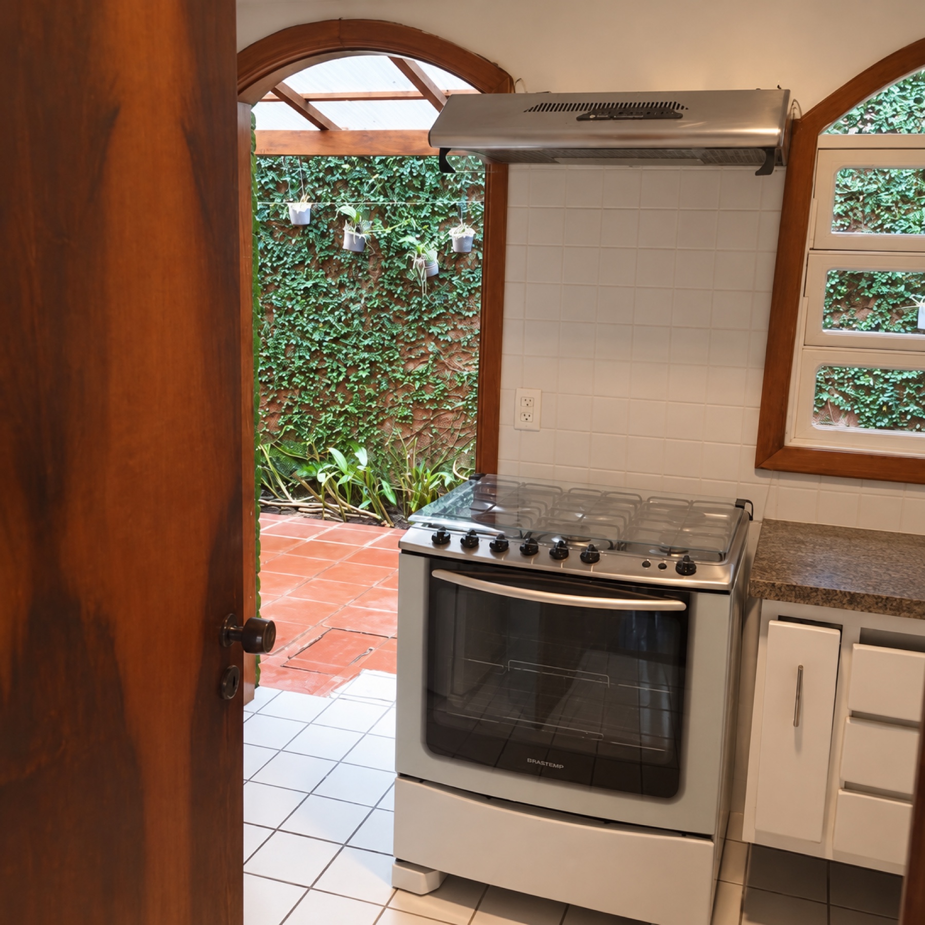 Cozinha com fogão e janela para o pátio verde