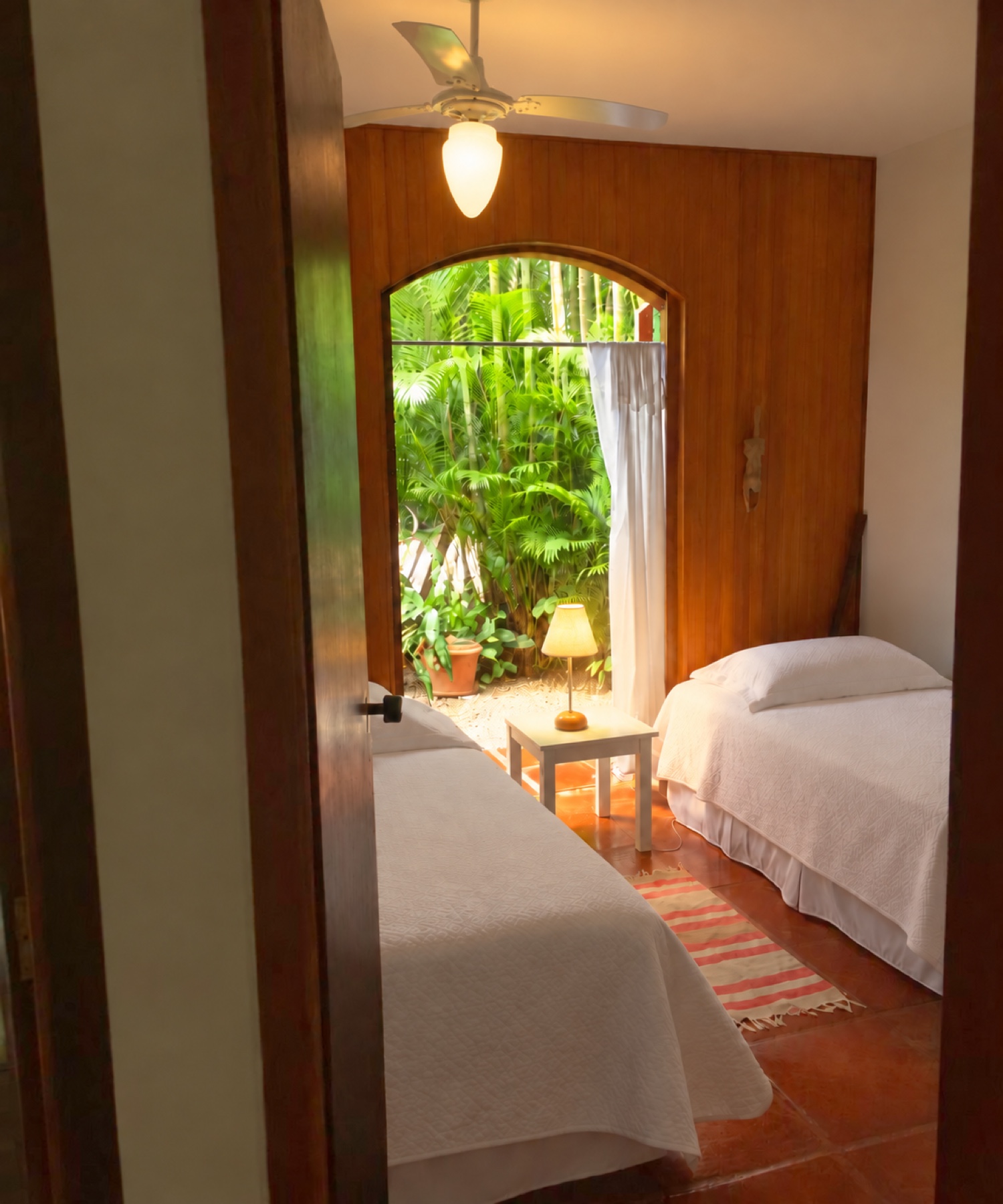 Quarto com duas camas de solteiro e porta em arco para o deck