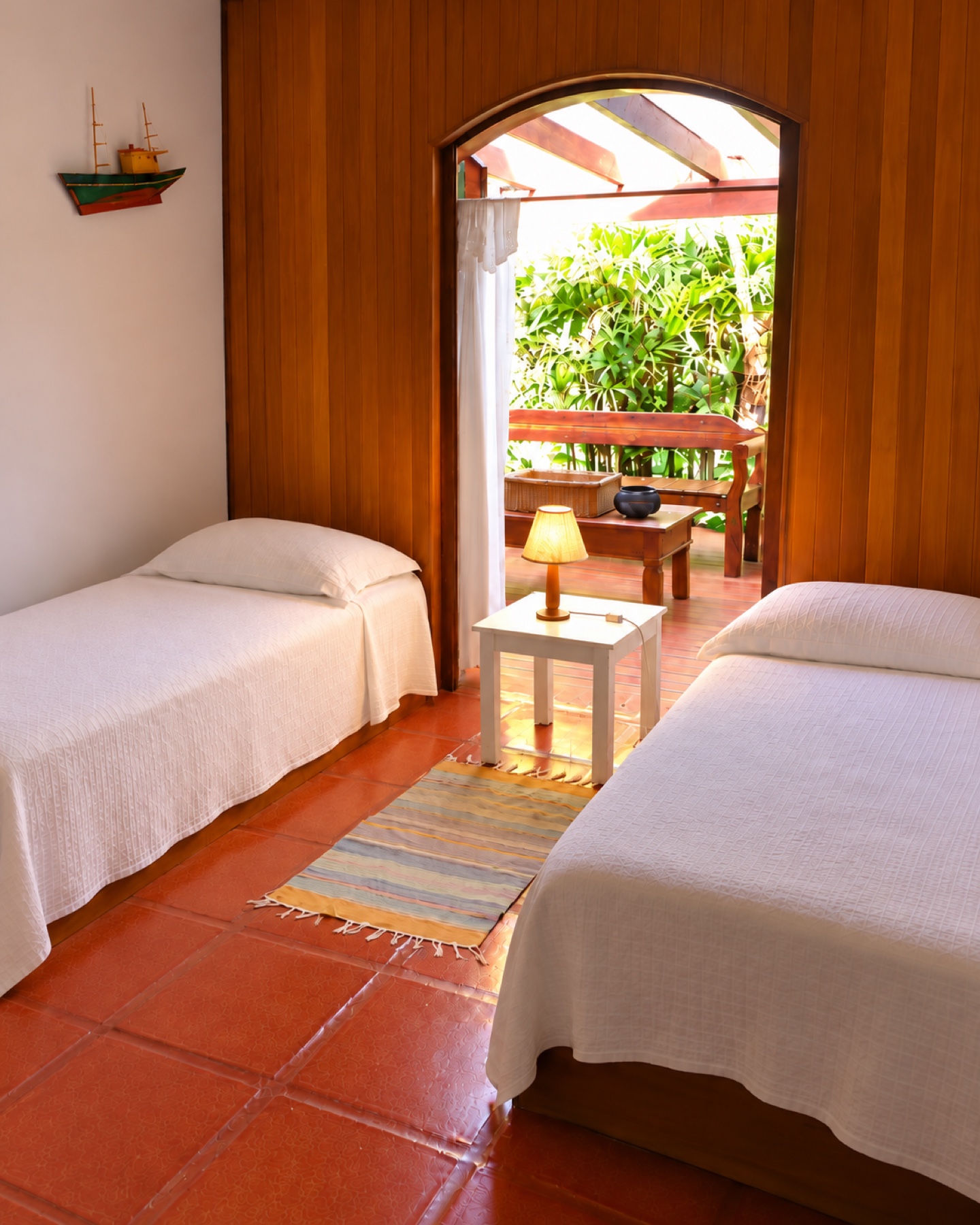 Quarto com duas camas de solteiro e porta em arco para o deck