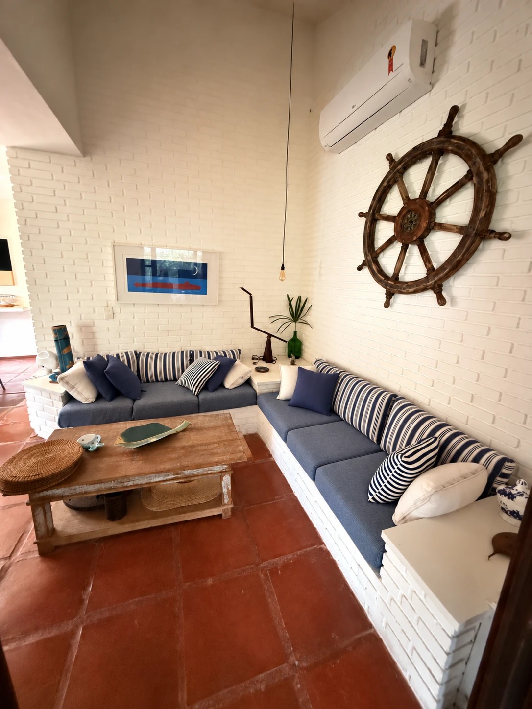 Sala de estar com sofá e timão na parede de tijolinho branco
